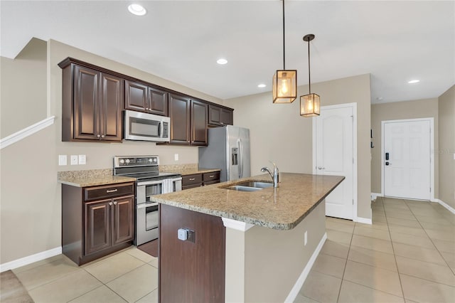 kitchen with sink, light stone countertops, an island with sink, dark brown cabinets, and stainless steel appliances