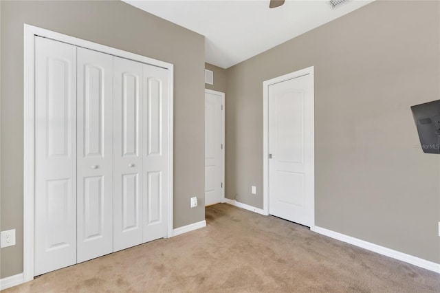 unfurnished bedroom with light carpet, a closet, and ceiling fan