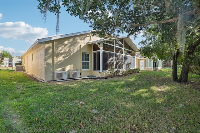 rear view of property with a sunroom, a yard, central AC unit, and ac unit