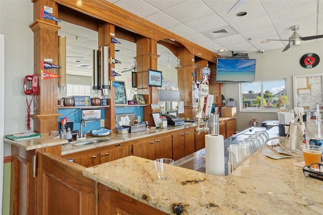 kitchen featuring a paneled ceiling, ceiling fan, light stone countertops, and sink