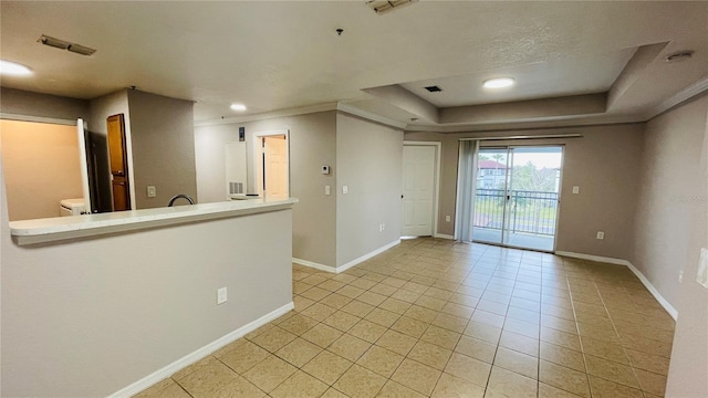 tiled spare room featuring a tray ceiling and ornamental molding