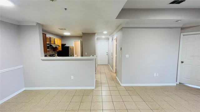 kitchen with light tile patterned floors, ornamental molding, and stainless steel refrigerator