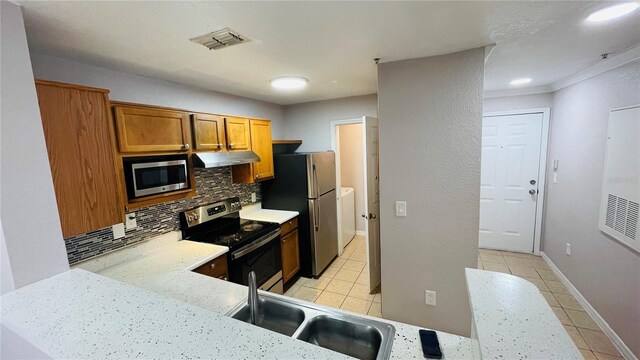 kitchen featuring sink, decorative backsplash, ornamental molding, light tile patterned flooring, and stainless steel appliances