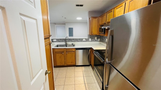 kitchen with light tile patterned flooring, appliances with stainless steel finishes, backsplash, and sink