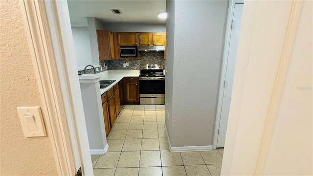 kitchen with light tile patterned floors, sink, appliances with stainless steel finishes, and tasteful backsplash