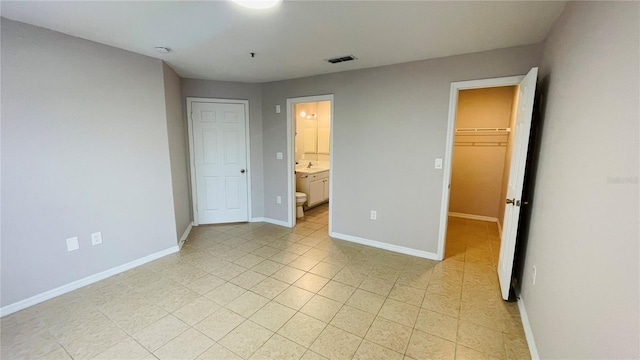 unfurnished bedroom featuring ensuite bath, a spacious closet, a closet, and sink