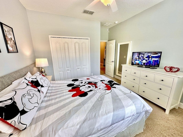 bedroom with ceiling fan, a closet, light carpet, and a textured ceiling