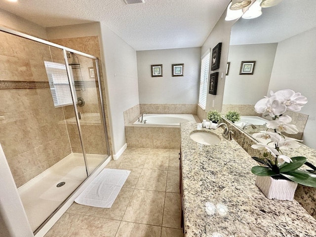 bathroom with a textured ceiling, vanity, tile patterned flooring, and independent shower and bath