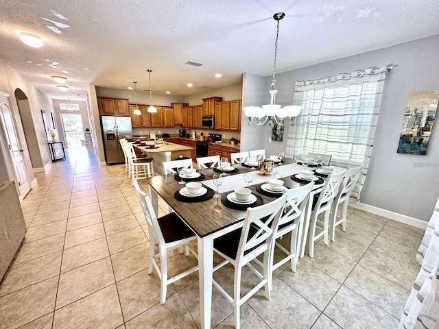 dining room with a textured ceiling, an inviting chandelier, and light tile patterned floors