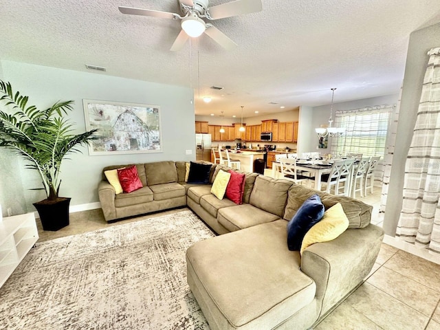 tiled living room featuring a textured ceiling and ceiling fan with notable chandelier