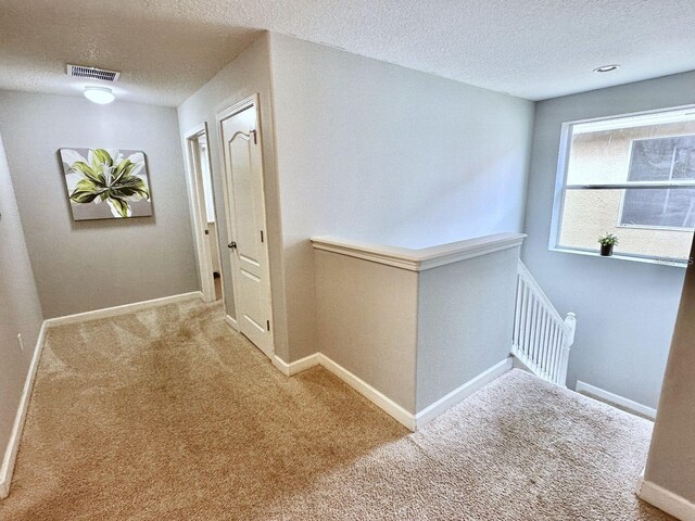 hall featuring a textured ceiling and carpet flooring