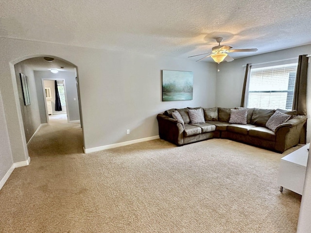 carpeted living room with a textured ceiling, ceiling fan, and a healthy amount of sunlight