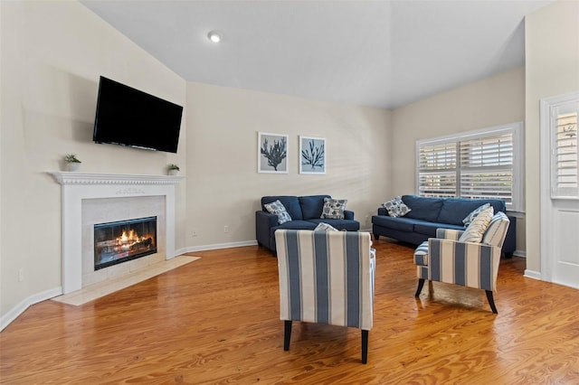 living room with a fireplace, vaulted ceiling, and hardwood / wood-style flooring