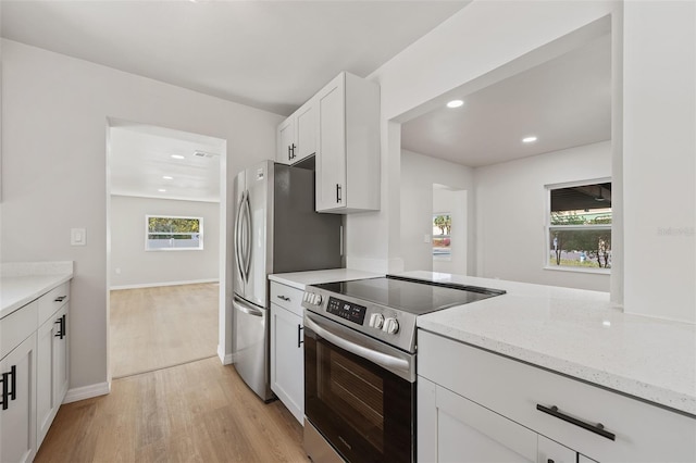 kitchen with white cabinets, plenty of natural light, light stone countertops, and stainless steel appliances