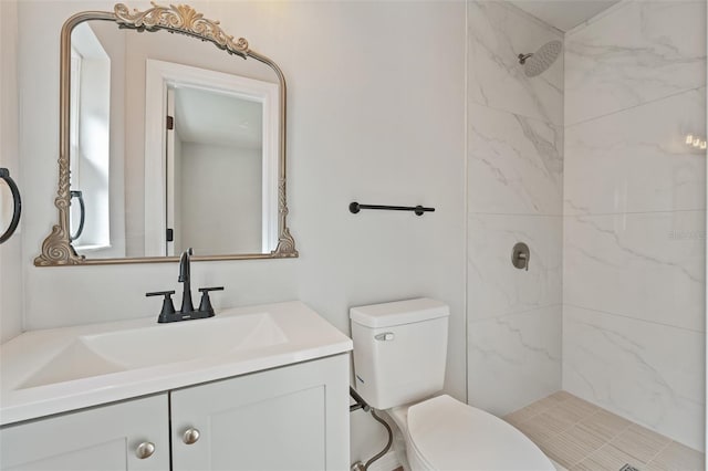 bathroom with tiled shower, vanity, and toilet