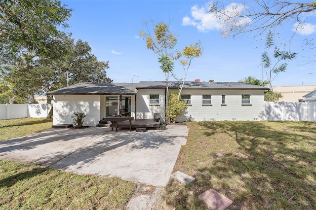 rear view of property featuring a patio, a wooden deck, and a lawn