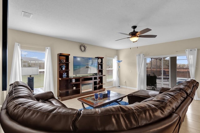 living room with a textured ceiling, ceiling fan, and light tile patterned flooring