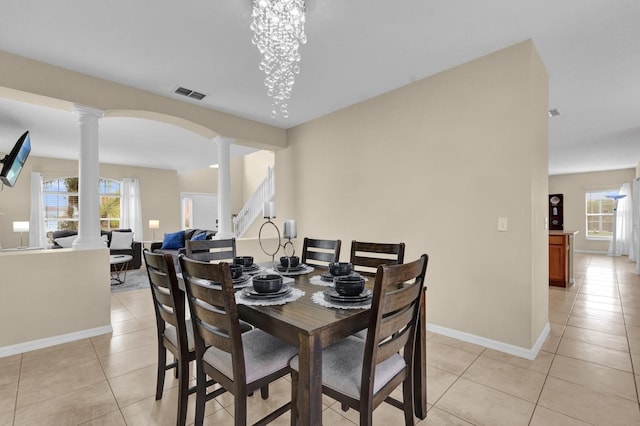 dining room with a chandelier, ornate columns, and light tile patterned flooring