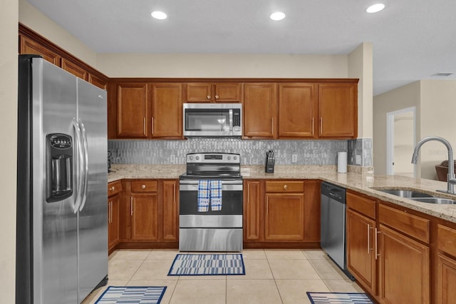 kitchen with light stone counters, sink, light tile patterned floors, and appliances with stainless steel finishes