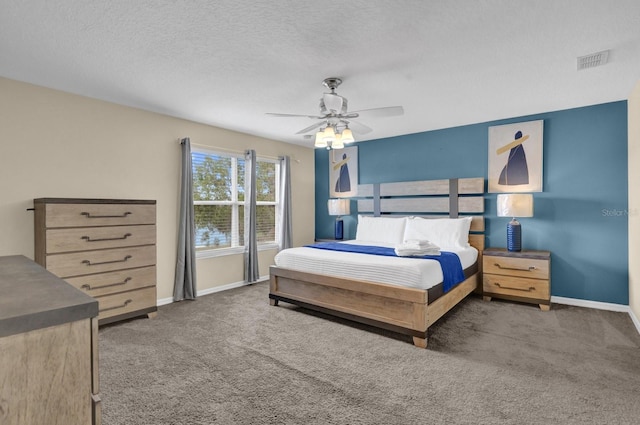 bedroom with ceiling fan, dark carpet, and a textured ceiling