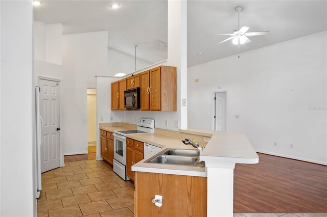 kitchen with kitchen peninsula, ceiling fan, white appliances, high vaulted ceiling, and sink