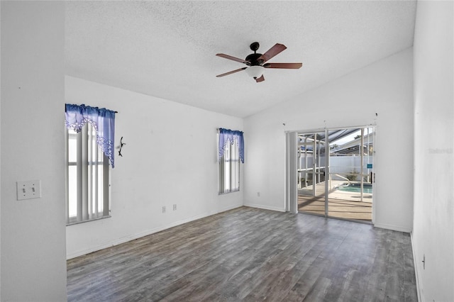 empty room featuring ceiling fan, vaulted ceiling, dark hardwood / wood-style flooring, and a healthy amount of sunlight