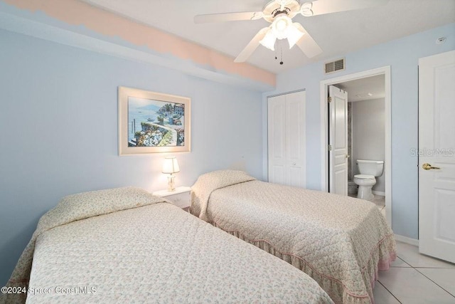 bedroom with light tile patterned floors, a closet, ensuite bath, and ceiling fan