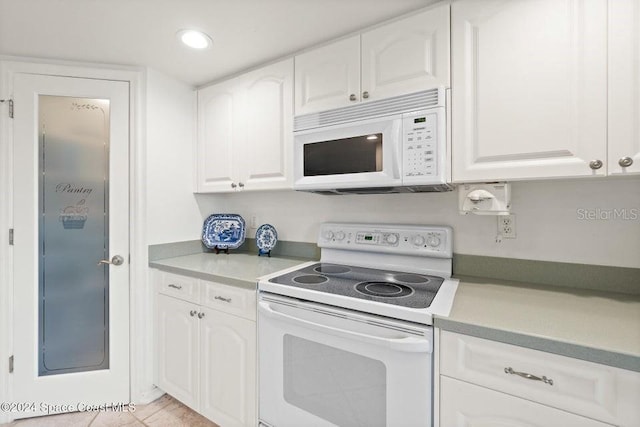 kitchen with white cabinets, light tile patterned flooring, and white appliances