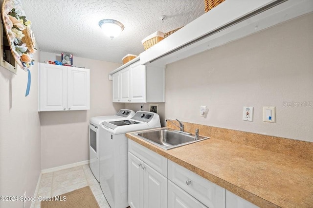 laundry room featuring sink, cabinets, washing machine and dryer, a textured ceiling, and light tile patterned floors