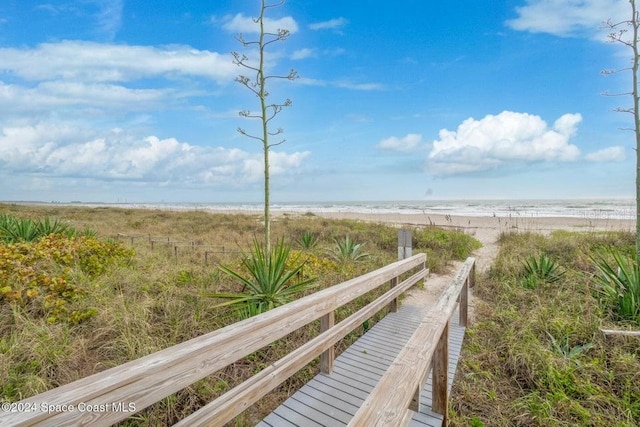 view of property's community with a water view and a beach view