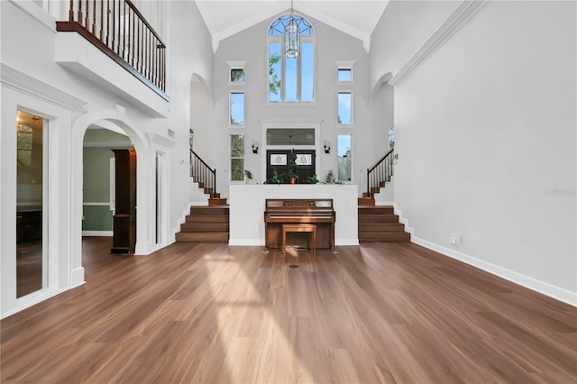 entrance foyer with french doors, a notable chandelier, crown molding, hardwood / wood-style floors, and a towering ceiling