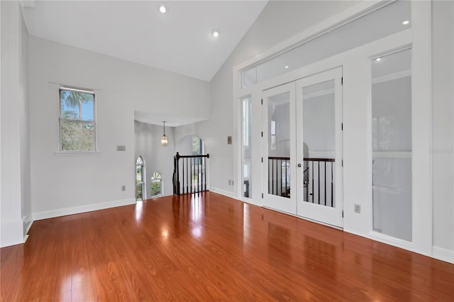 spare room featuring hardwood / wood-style floors, high vaulted ceiling, and french doors