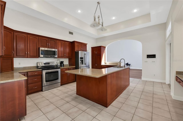 kitchen with decorative light fixtures, stainless steel appliances, light tile patterned floors, and a kitchen island