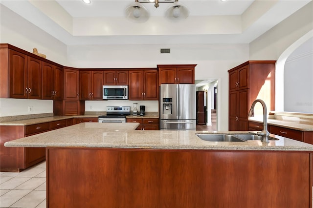 kitchen with light tile patterned floors, stainless steel appliances, a tray ceiling, and sink