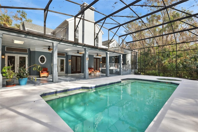 view of pool featuring ceiling fan, a patio area, glass enclosure, and french doors