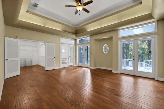 unfurnished bedroom featuring ceiling fan, french doors, a raised ceiling, wood-type flooring, and access to outside