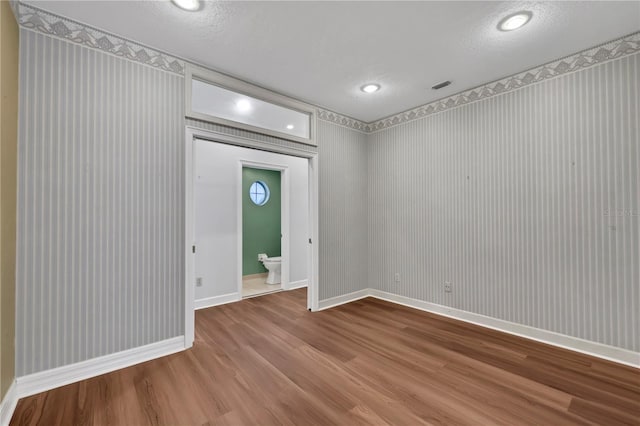 empty room with a textured ceiling and hardwood / wood-style flooring