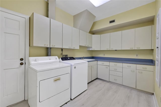 laundry room featuring washer and dryer, cabinets, light wood-type flooring, and sink