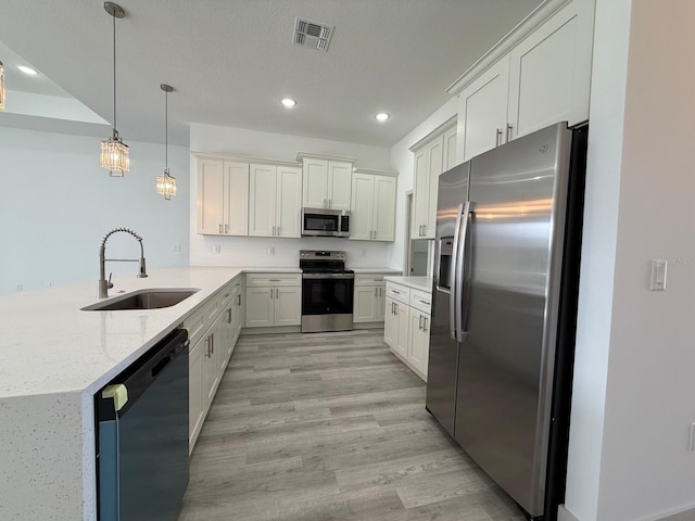 kitchen with sink, stainless steel appliances, light stone counters, kitchen peninsula, and pendant lighting