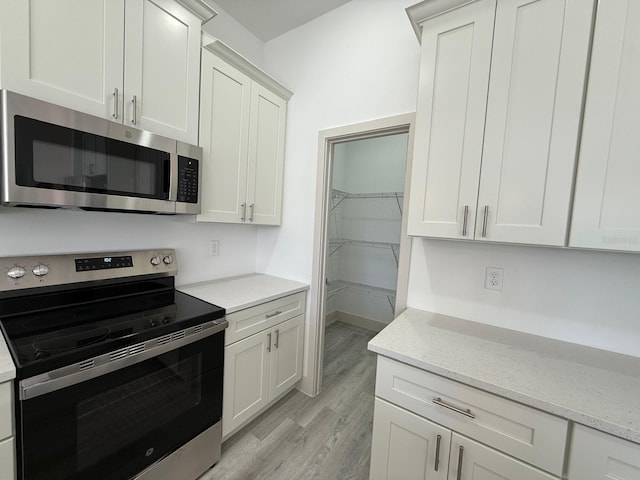 kitchen featuring white cabinets, light stone countertops, and stainless steel appliances