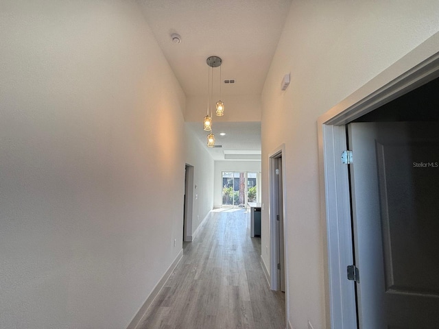 hallway with a high ceiling and light wood-type flooring