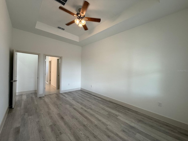 unfurnished bedroom with a raised ceiling, ceiling fan, and wood-type flooring