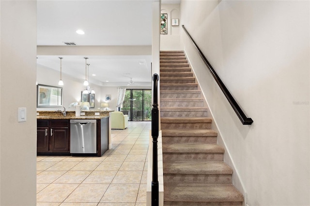 staircase featuring tile patterned flooring, ceiling fan, and sink