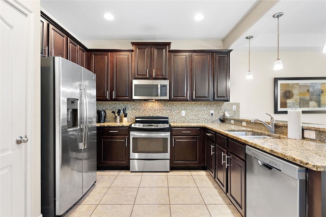 kitchen featuring sink, hanging light fixtures, light tile patterned floors, dark brown cabinetry, and stainless steel appliances