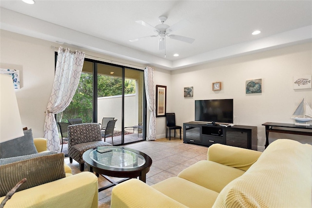 tiled living room with ceiling fan and a tray ceiling