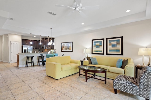 tiled living room with a raised ceiling and ceiling fan