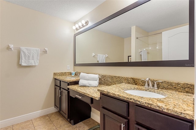 bathroom featuring tile patterned flooring, vanity, a textured ceiling, and tiled shower