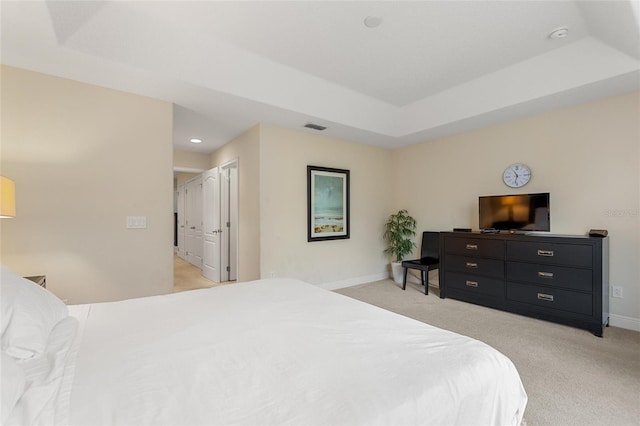 bedroom with a tray ceiling, a closet, and light colored carpet