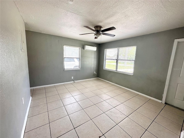 empty room with a textured ceiling, a wall unit AC, ceiling fan, and light tile patterned flooring