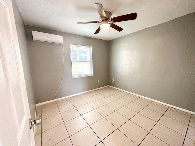 spare room with ceiling fan, an AC wall unit, a textured ceiling, and light tile patterned floors